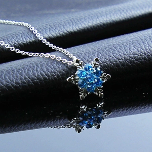 Silver Frozen snowflake necklace with sparkling blue crystals on black leather background