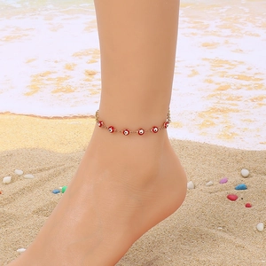 18K gold-plated anklet with red evil eye beads worn by a woman on a sunny beach