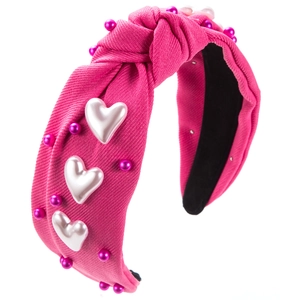 Détail du serre-tête noué fuchsia avec cœurs blancs et perles roses sur tissu côtelé