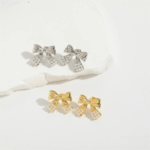 Elegant bow knot pearl stud earrings in gold and silver finishes on white stone