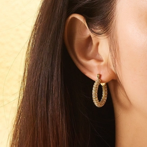 Close-up of 18k gold plated hoop earrings with rows of sparkling zircon stones on ear