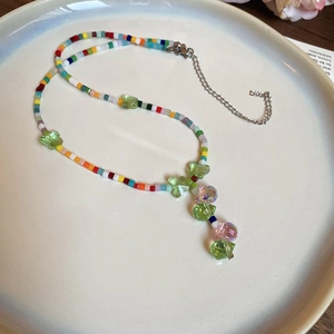 Detail of colorful beaded necklace with green butterfly charms and a crystal pendant