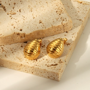 Gros plan sur les boucles d'oreilles dorées en forme de larme avec texture rayée horizontale