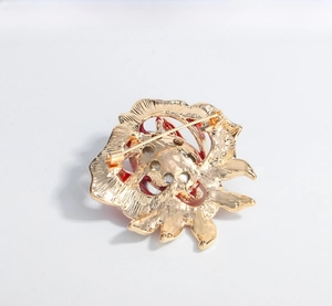 Detailed back view of a vintage rose brooch with a gold-tone alloy pin and red enamel finish