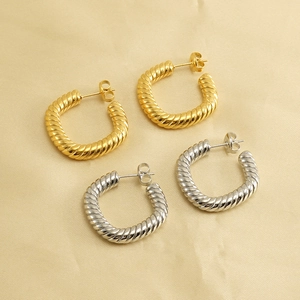 Pair of 18K gold and silver plated twisted rope hoop earrings on silk background