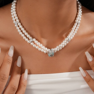 Detail of double-layer pearl necklace with blue gemstone pendant and rhinestone flowers