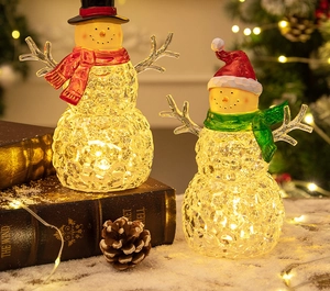 Macro detail of glowing crystal snowman figurines with LED lights on a snowy background