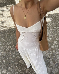 Detail of white jacquard strap dress paired with gold pendant necklace and tote bag
