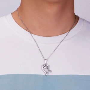 Close-up of stainless steel key and heart puzzle pendant necklace on model neck