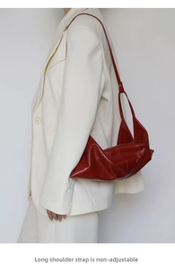 Detail of red leather croissant bag featuring a non-adjustable shoulder strap design