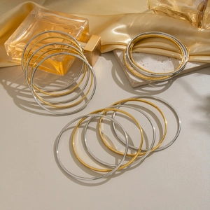 Minimalist gold and silver stainless steel stacked bangle set with smooth textured finishes
