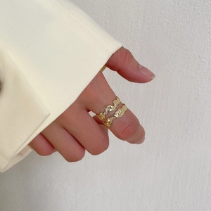 Close-up of golden irregular lava texture ring on finger with minimalist white background