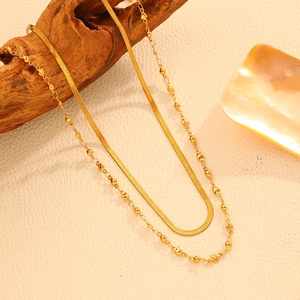 Détail d'un collier double rang en acier doré avec chaîne serpent et pendentif cœur
