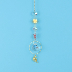 Detail of crystal suncatcher with moon fairy charm and faceted glass ball on blue sky