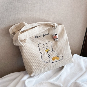 Off-white corduroy tote bag with embroidered cartoon bear and cow charm accessory