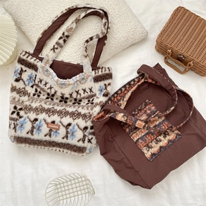Detail of plush jacquard tote bag and canvas bag with leather brand tag on white fabric