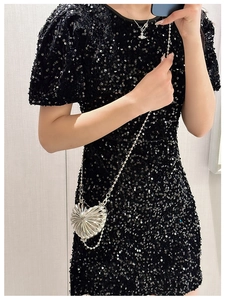 Detail of a heart-shaped silver metallic mini bag with a radiant texture on evening dress