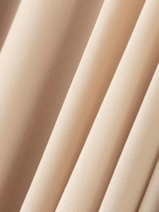 Macro detail of beige chiffon fabric showing delicate layered pleats and fine texture