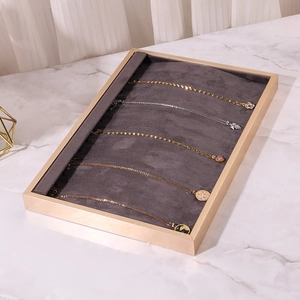 Macro view of beige necklace display tray with dark grey velvet lining and gold frame