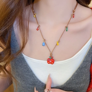Gros plan d'un collier avec pendentif pomme coloré et cordon tressé porté par un mannequin