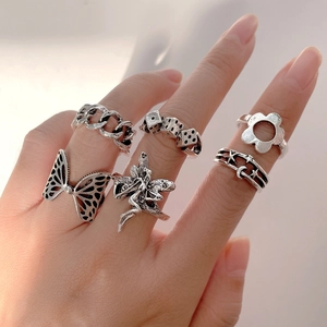 Close-up of six silver gothic rings featuring butterfly, elf, and moon motifs on a hand