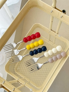 Detailed view of colorful beaded handle stainless steel forks in a cream metal basket