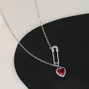 Detail of safety pin necklace with a red heart gemstone and micro-pave crystals