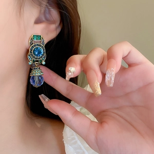Vintage palace style drop earrings with blue crystals shown on a female model