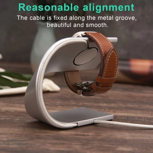 Minimalist silver aluminum C-shape Apple Watch stand with sleek cable management on wood desk