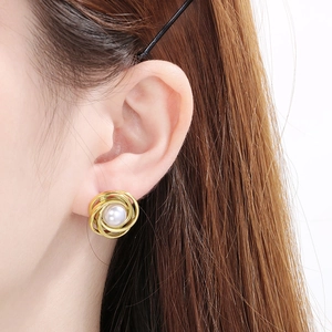 Macro shot of French style pearl stud earring with golden spiral metal textured detail