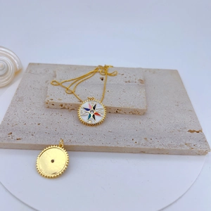 Detail of gold-plated sunburst compass pendant with colorful enamel and zircon inlay