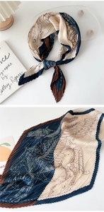 Detail of pleated silk scarf with navy and beige equestrian pattern on a white desk