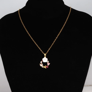 Détail d'un collier doré avec pendentif couronne de fleurs et papillon sur buste noir