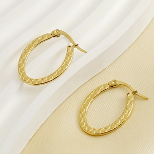 Detailed close-up of oval gold earrings featuring a unique honeycomb textured surface