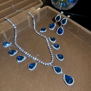 Macro shot of silver jewelry set with teardrop blue gems in a luxury velvet box