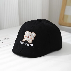 Détail de la broderie ours sur béret noir pour bébé avec jeux d'ombres artistiques