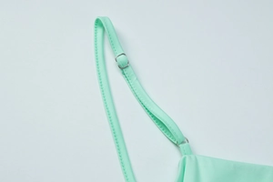 Detail of mint green elastic strap with silver metal buckle on a knitted dress