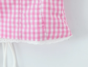 Close-up of pink checkered fabric with white hollow embroidery lace hem detailing