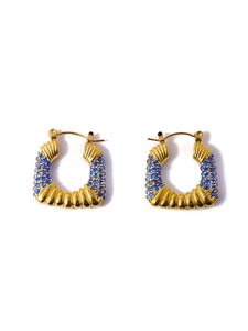 Detailed close-up of C-shaped golden earrings with micro-set blue gemstones and baroque texture