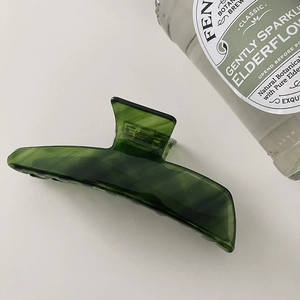 Detail of green marble acetate hair claw clip showing glossy texture and elegant patterns