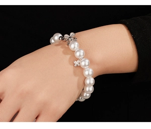 Detail of 925 sterling silver pearl bracelet with sparkling clover charms on a wrist