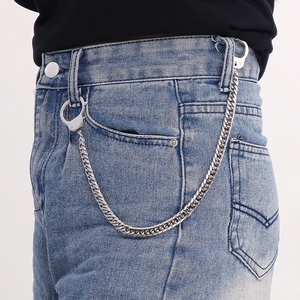 Détail de la chaîne de pantalon gourmette argentée avec fermoirs menottes sur un jean