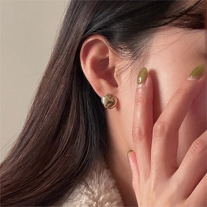 Minimalist 925 sterling silver heart earrings with polished gold finish on female model