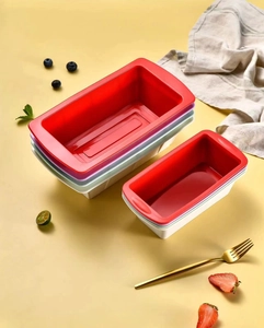 Stack of colorful silicone loaf pans with red, purple, and green baking molds on a table