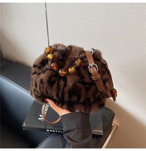 Detail of leopard print faux fur bucket bag with amber beaded handle and leather strap