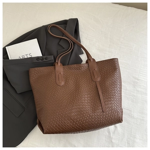 Gros plan détaillé du sac cabas tressé marron foncé montrant la texture du cuir premium