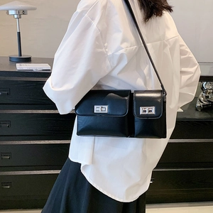 Detail of black double-pocket crossbody bag with silver twist lock and wide strap