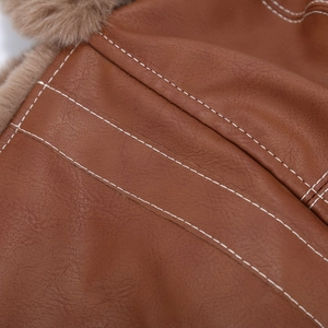 Macro detail of brown leather aviator hat with white stitching and plush faux fur lining