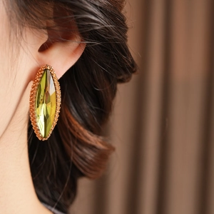 Close-up of olive green marquise gemstone stud earrings with gold plating on model