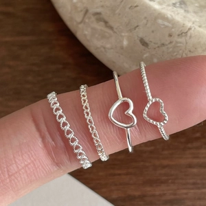 Detailed view of four 925 sterling silver heart rings with hollow and twisted textures